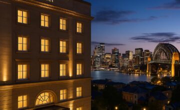 The Langham Sydney hotel exterior with city skyline and Harbour Bridge at dusk