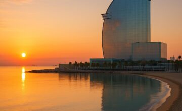 W Barcelona sail-shaped hotel reflecting golden sunrise over the beach and sea