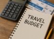 Person planning a travel budget with calculator and tickets