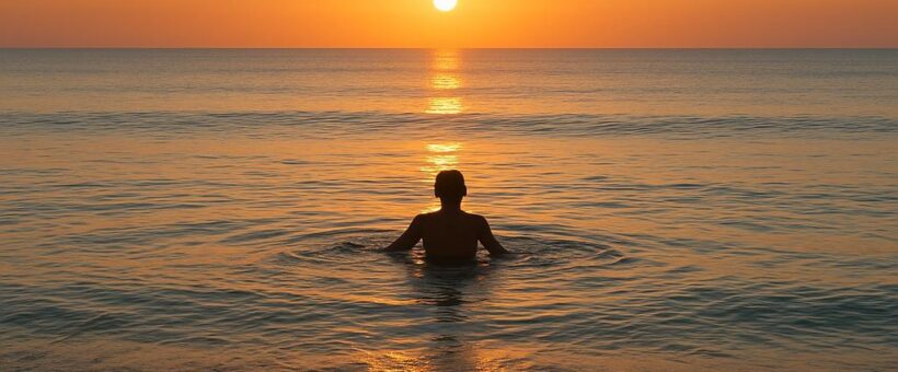Solo swimmer at calm sunrise beach