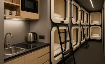 Modern capsule hotel kitchenette with sleeping pods visible