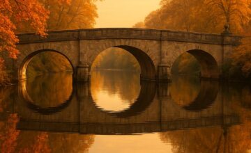 Historic stone bridge at golden hour with calm water reflections
